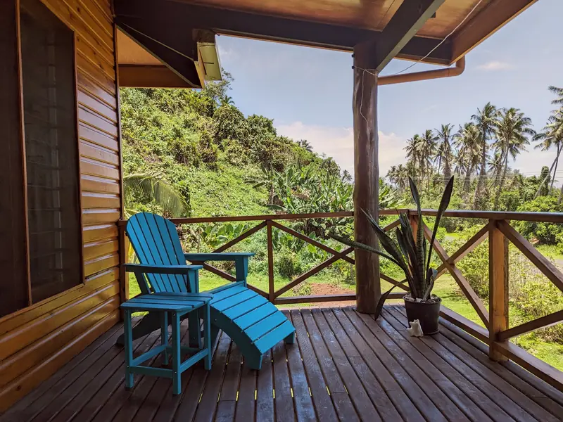 Two blue deck chairs on the wooden verandah looking out to the palms